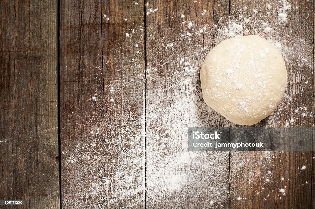 Ball of pizza dough on a rustic wooden background Traditional pizza dough, proved and ready to be made into a delicious stone baked pizza. On a rustic textured wooden background, dusted with flour Pizza Stock Photo
