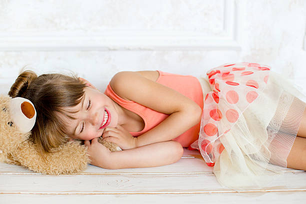 kleine ballerina schläft auf einem teddy bear - ballet dress studio shot costume stock-fotos und bilder