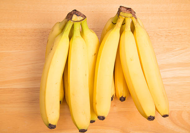 istock Two Bunces of Yellow Bananas on Wood Table 505194119