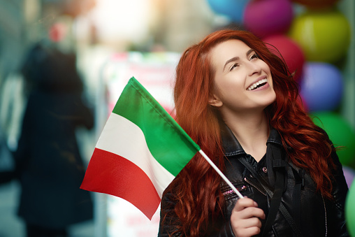 photo of attractive woman laughing, walking in Rome and holding Italian flag.looking away and enjoying her day.