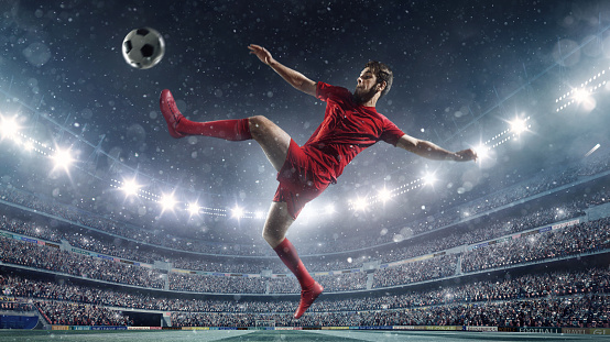 Professional footballer kicking ball during game in floodlit soccer stadium full of spectators under stormy sky and floodlights. It's snowing up there.
