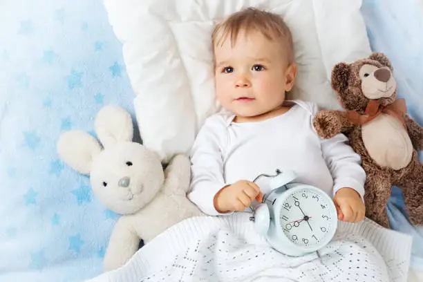 Photo of One year old baby with alarm clock