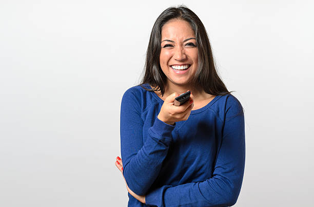 Laughing woman pointing television remote control