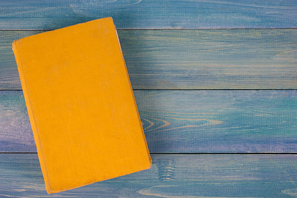 istock Yellow book on blue wooden background 505215518