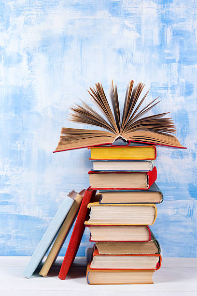 istock Stack of colorful hardback books, open book on blue background 505216230