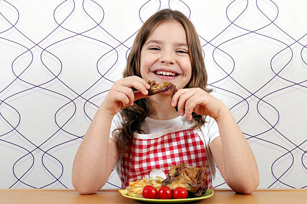 happy little girl eating chicken wings stock photo
