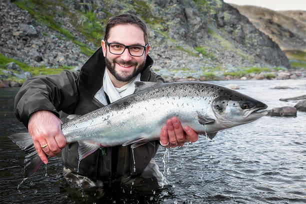 istock fisherman holding a fresh caught salmon 505228549
