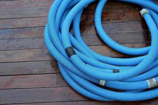 Swimming pool vacuum cleaner hose on wood floor