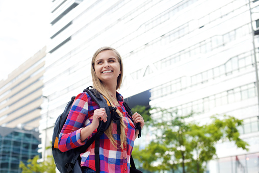 Portrait of a smiling female college student walking with bag