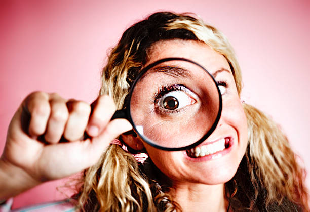istock Humorous look at blonde nerd's eye distorted by magnifying glass 505232201