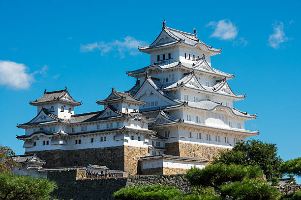 Himeji, Japan - October 7, 2015: Himeji's white castle against a blue sky on a clear Autumn morning. Also known as Hakuro-jo, it is regarded as the finest surviving example of prototypical Japanese castle architecture, and it is one of Japan's \