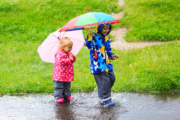 istock little boy and girl having fun on rain 505245382