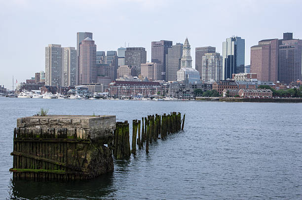 Old pilings and Boston skyline The remnants of an old pier across the harbor from Downtown Boston. east boston stock pictures, royalty-free photos & images