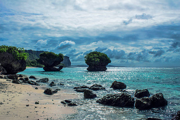 Large Rocks In Ocean A picture of a large rock in a beautiful ocean at Tanguisson Beach in Guam. guam stock pictures, royalty-free photos & images