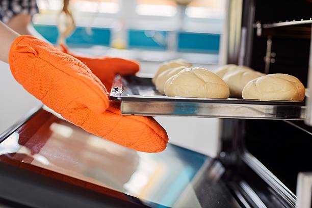 istock women hand taking out  rolls from the oven. 505259196