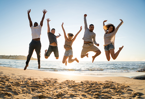 Excited group of Australian friends jumping at the beach and having fun