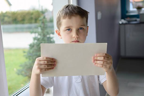 istock sad boy holding an empty copyspace sheet of paper 505260444
