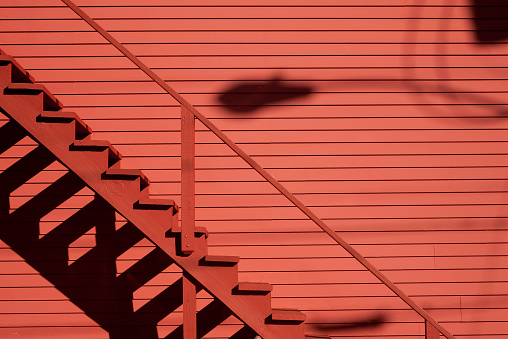 Red staircase on the red barn with shadows