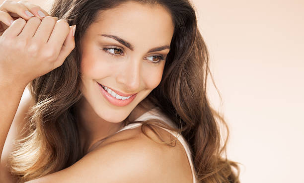 Happy Beautiful Woman Happy beautiful young woman with long hair smiling over beige background. Fashion and beauty concept in studio. tooth in hand stock pictures, royalty-free photos & images