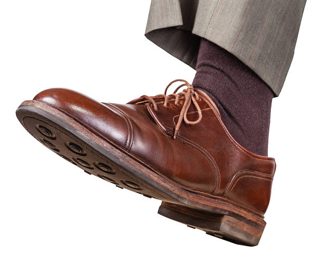 male left foot in brown shoe takes a step isolated on white background