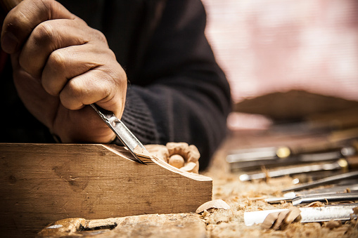 An engraver is carving a piece of wood frame