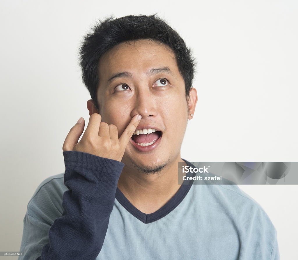 Hombre asiático meter el dedo en la nariz - Foto de stock de Aburrimiento libre de derechos
