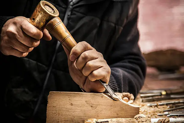 An engraver is carving a piece of wood frame