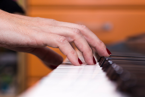 Close-up of hands playing the piano at home