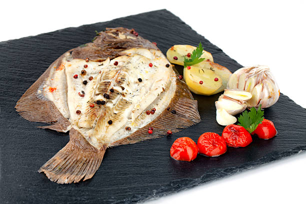 Plate With Baked Turbot Fish Plate with baked turbot fish with potato slices, seasoned with cherry tomatoes, garlic, parsley, thyme, black and red pepper grains. turbot stock pictures, royalty-free photos & images