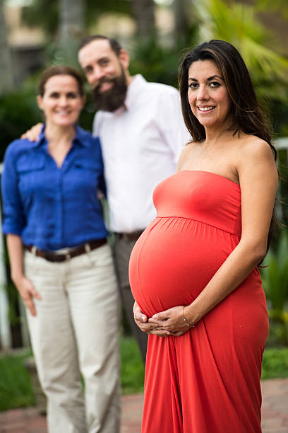 Surrogate Mother Pregnant Hispanic surrogate mother posing with the babies future parents surrogacy stock pictures, royalty-free photos & images