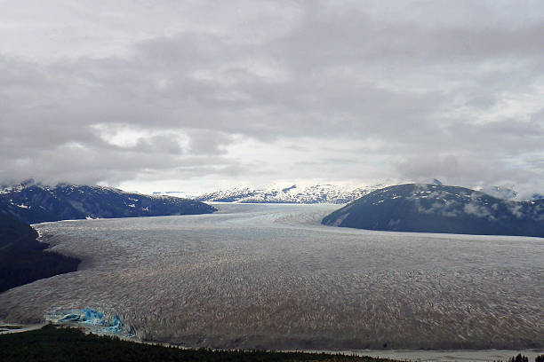 The Norris Glacier, Juneau Icefield, Juneau, Alaska The Juneau Icefield is an ice field located just north of Juneau, Alaska and continues north through the border with British Columbia and is the fifth-largest ice field in the Western Hemisphere. The icefield is the source of many glaciers including the Mendenhall Glacier and the Taku Glacier. The icefield is home to over 40 large valley glaciers and 100 smaller ones.  alaskan icefield stock pictures, royalty-free photos & images