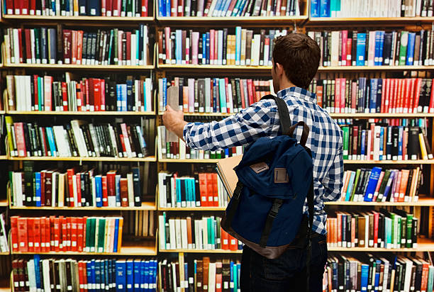 istock Rear view of student holding books in library 505304118