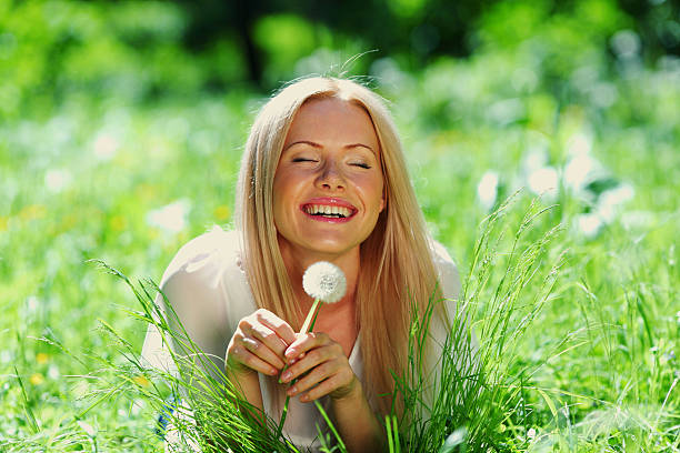 Girl blowing seeds from a flower dandelion in the autumn afternoon
