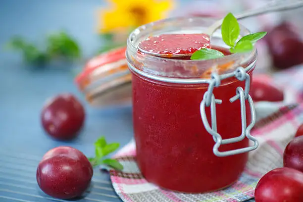cherry plum jam with a bank on a wooden table
