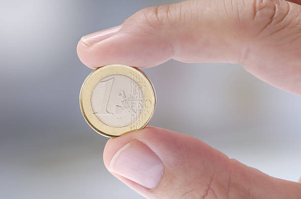 ein-euro-münze zwischen zwei fingern - ein euro stock-fotos und bilder