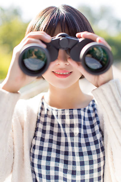 Young woman with binoculars travelling in nature, bird watching