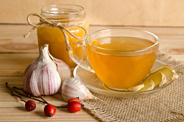 Cup of tea and twigs near wild rose Cup of tea with ginger slices . Home antimicrobial therapy garlic clove photos stock pictures, royalty-free photos & images
