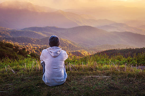 istock man sitting on hill in mountain landscape 505338430