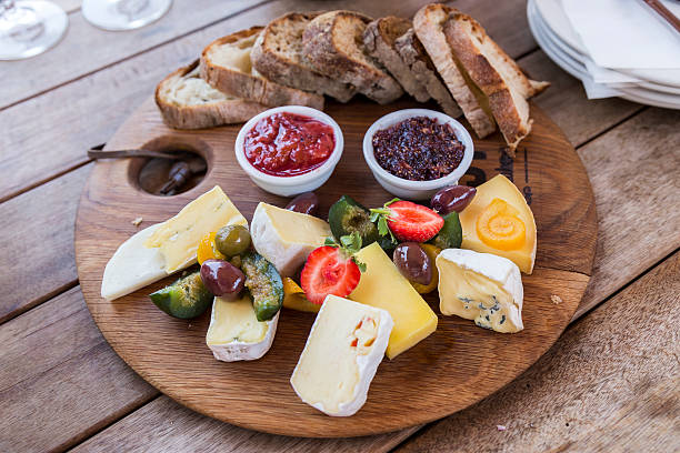 Delicious Platter Delicious cheese platter on a wooden board, with figs, olives, strawberry, homemade jams and tasty bread. plate fig blue cheese cheese stock pictures, royalty-free photos & images