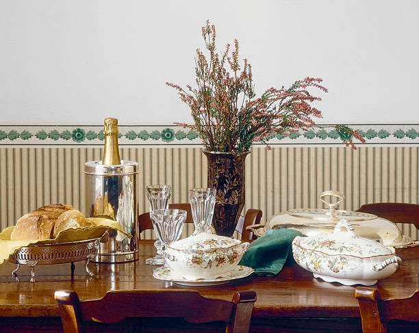 Horizontal shot of golden bronze elegant table with four seats, ready for a formal event, banquet or wedding, featuring pearly white decorated plates, silverware in order of use and chairs with matching sequins covers.