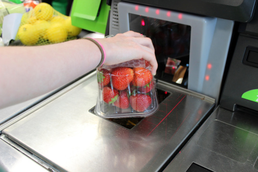 Chica de barrido (fresas) de compras en el supermercado servicio de check-out hasta (de compra) photo