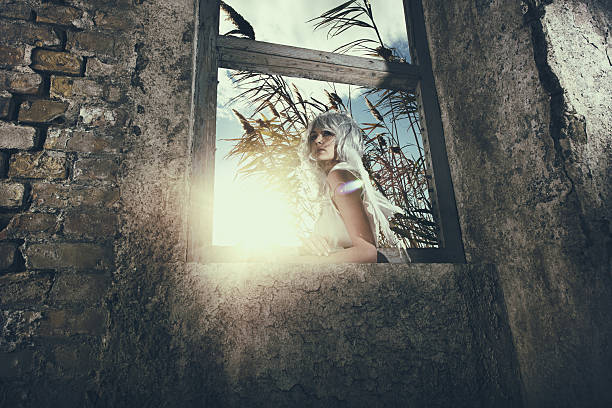 Low angle view of a pensive female angel on a window frame. The photo is taken from the inside while an angel is outside.
