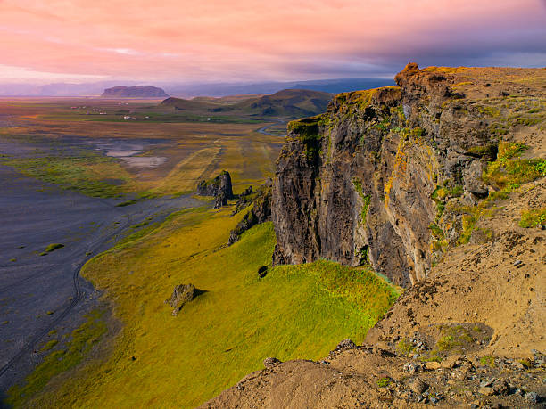 Dramatic rocky coastline landscape with green steep slopes, wild rocks and black beach, Iceland