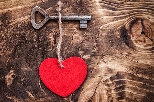 Love concept. An Old key and a heart on wooden background