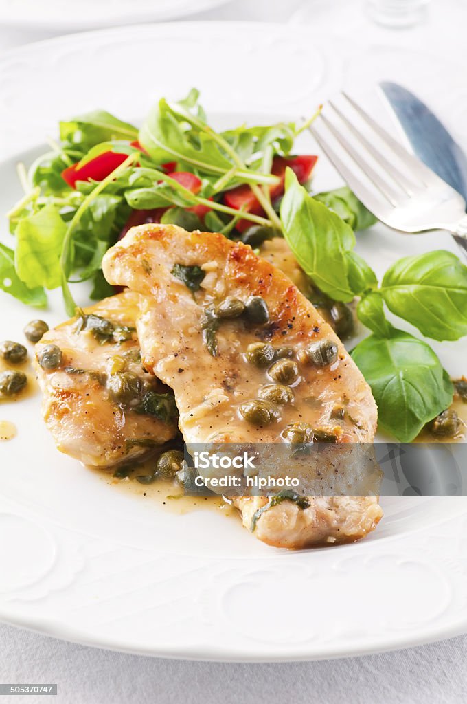 Chicken Piccata with Capern and Salad Chicken piccata with capern and salad as closeup on a white plate Italian Culture Stock Photo