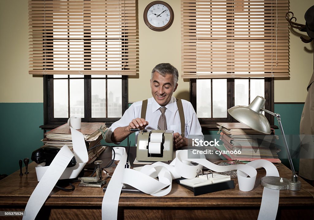Busy vintage accountant with calculator Busy vintage accountant with adding machine surrounded by cash register tape. Old-fashioned Stock Photo