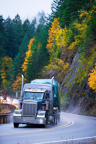 istock Semi truck trailer with cargo on winding autumn rain reoad 505375744