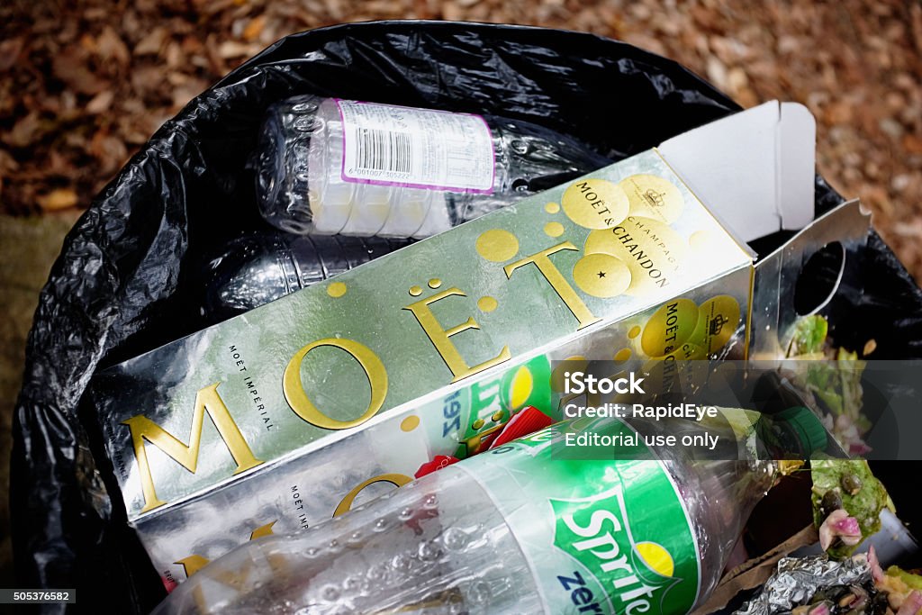 When the party's over: discarded Moet et Chandon champagne carton Natures Valley, South Africa - January 10, 2016:  Nature's Valley, South Africa  After a party, a box that held a bottle of Moet & Chandon champagne lies discarded with other rubbish in a trash can. Close up. Alcohol - Drink Stock Photo