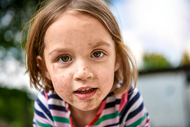 Little kid with dirty face from playing outside in dirt
