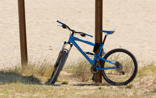 Blue mountain bike parked on a sandy beach